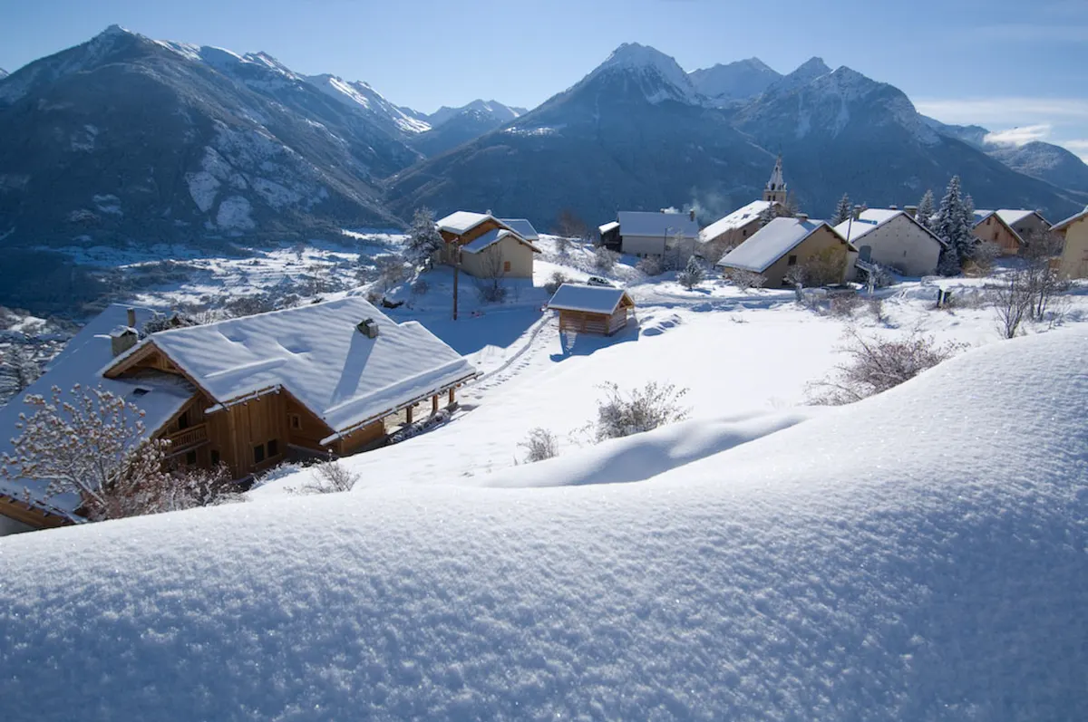 Vallée enneigée de Serre Chevalier, chalets et sommets sous un ciel clair