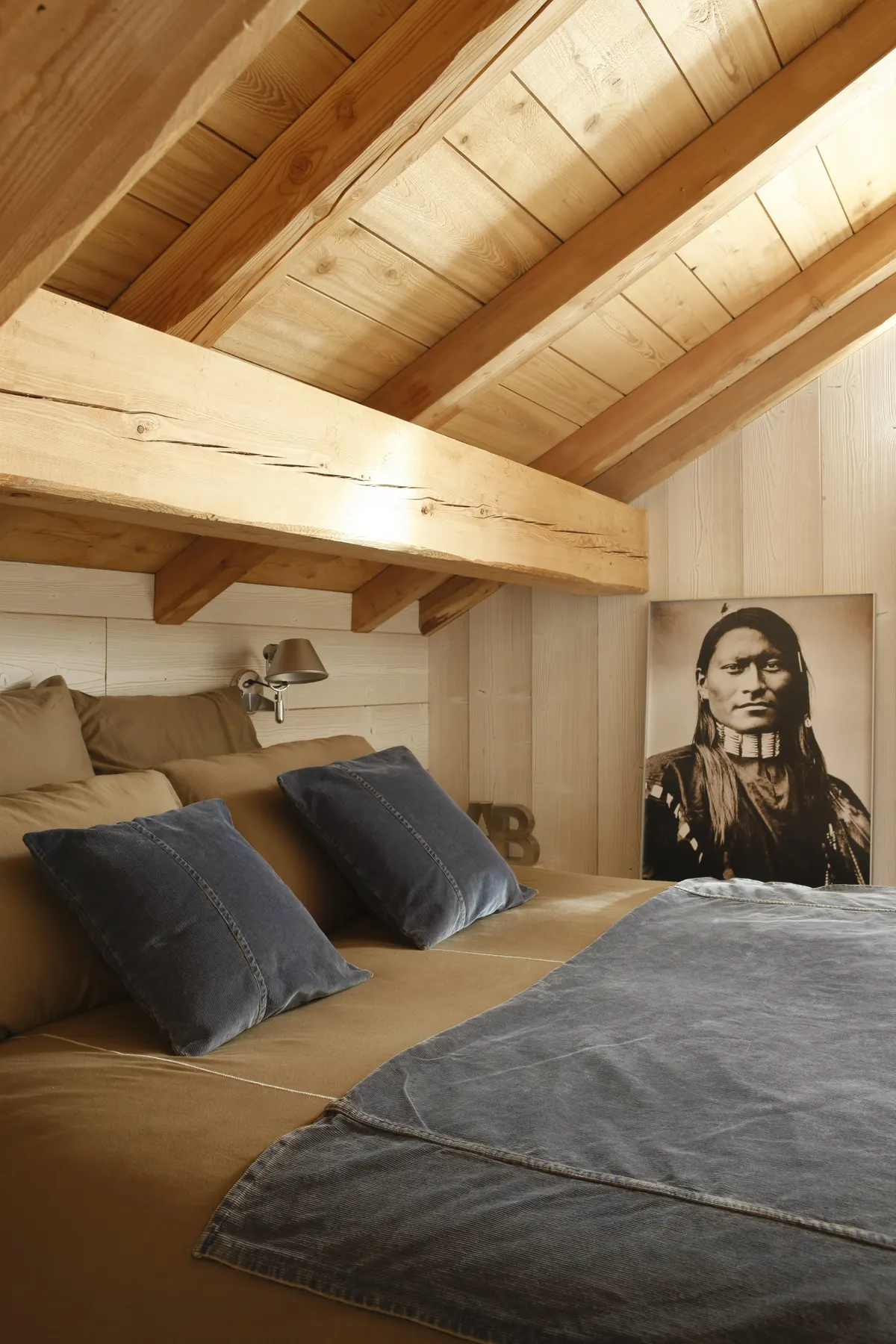 Chambre Blanche sous les poutres claires, coussins gris et portrait en noir et blanc
