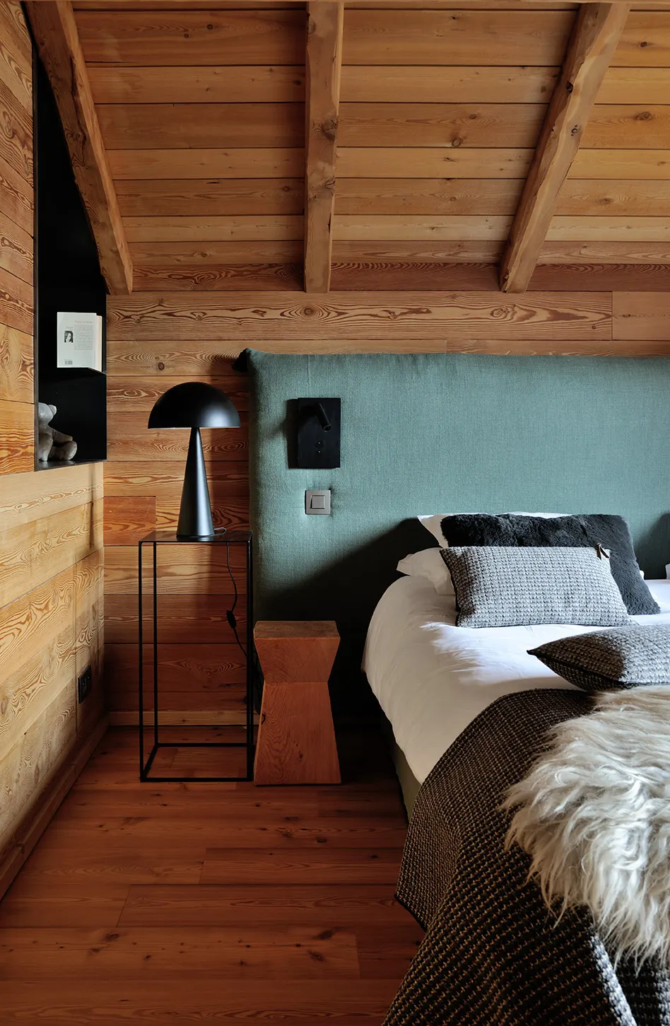 Lit habillé de gris et fourrure devant une tête de lit vert kaki
