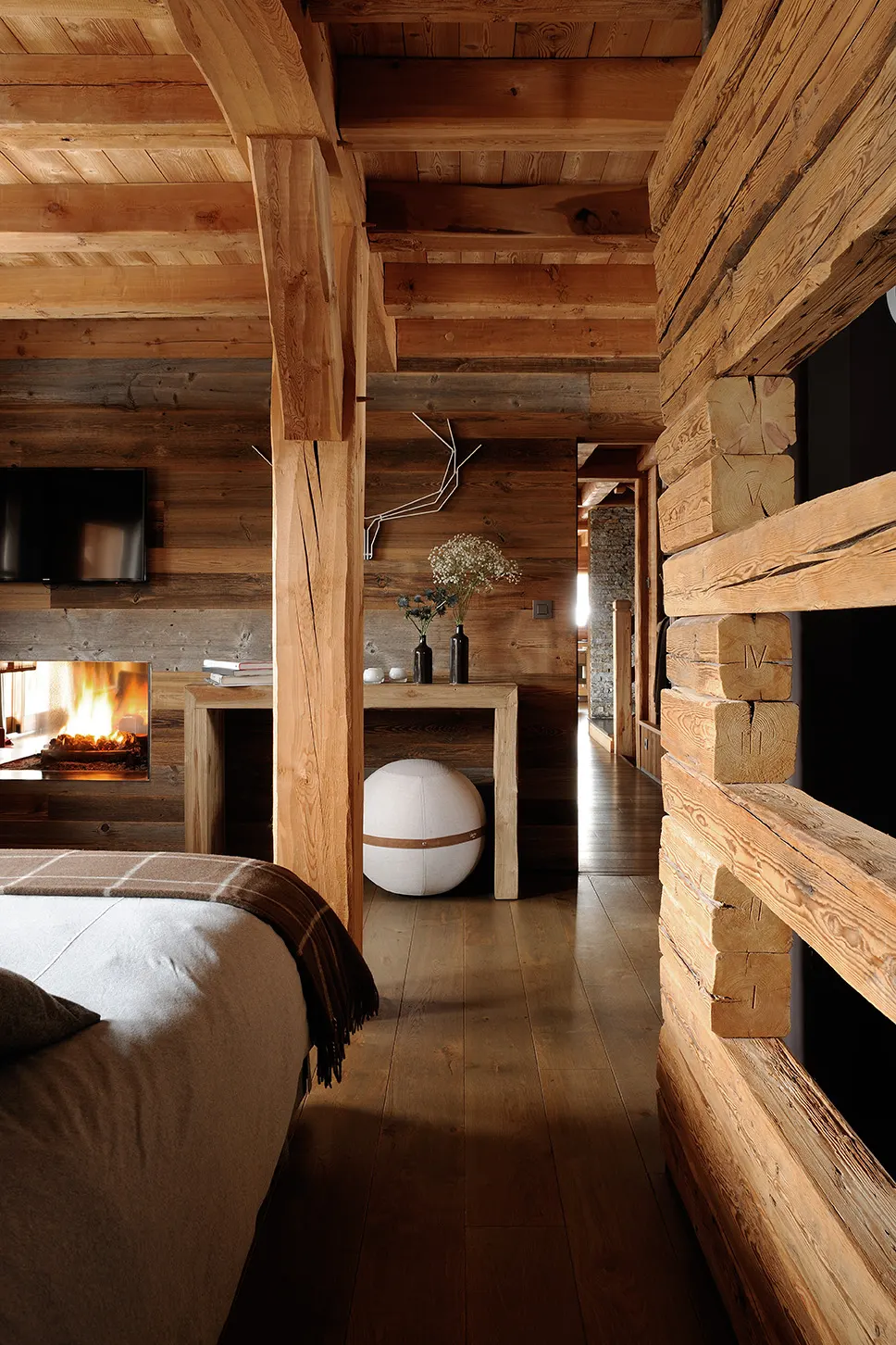 Chambre en bois de mélèze avec cheminée et lit habillé de lin