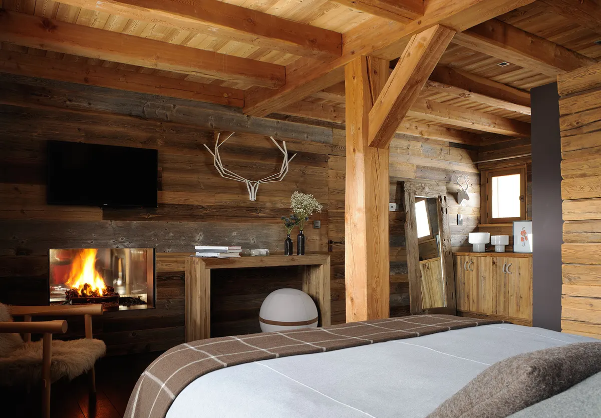 Chambre master, lit king size face à la cheminée allumée, trophée de cerf au mur