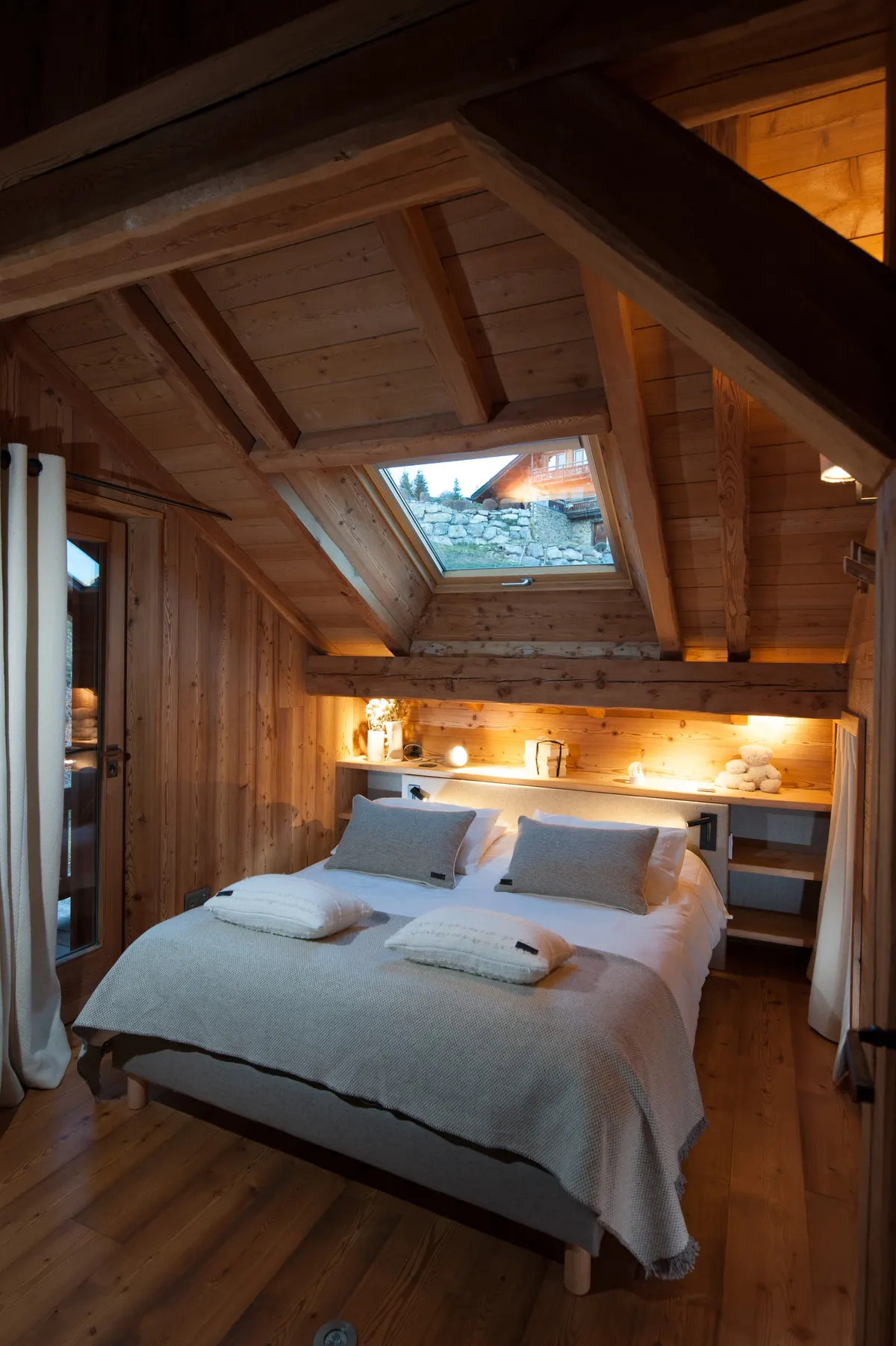 Chambre parentale mansardée, lit double sous le velux et éclairage chaleureux
