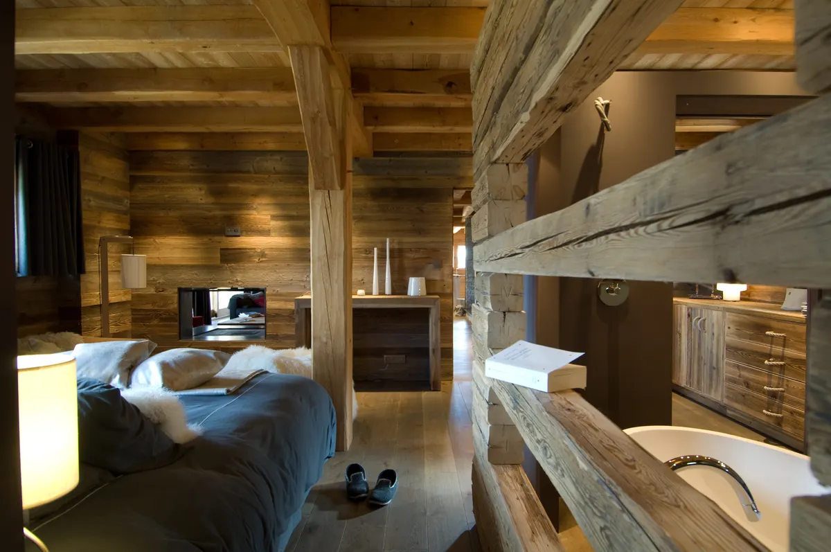 Chambre sous les poutres de mélèze, cloison en madriers et lumière douce
