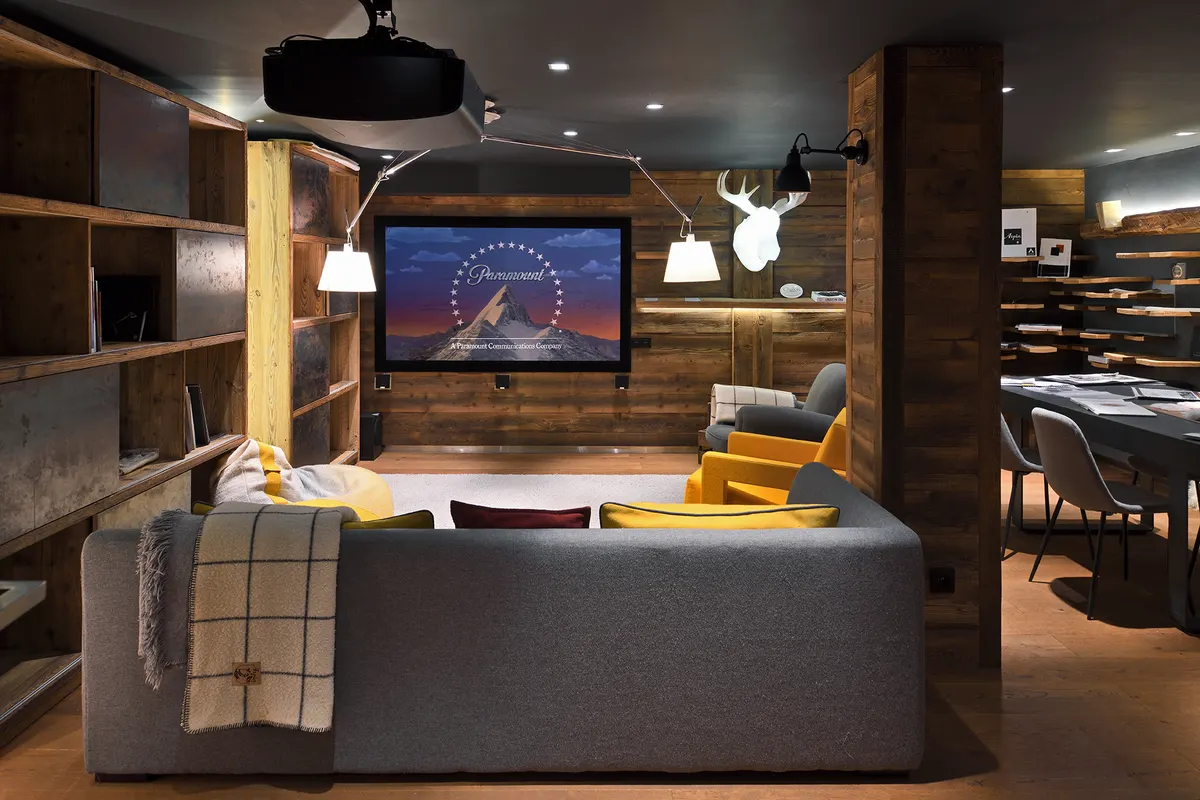 Home cinéma, grand écran, canapé gris et poufs colorés