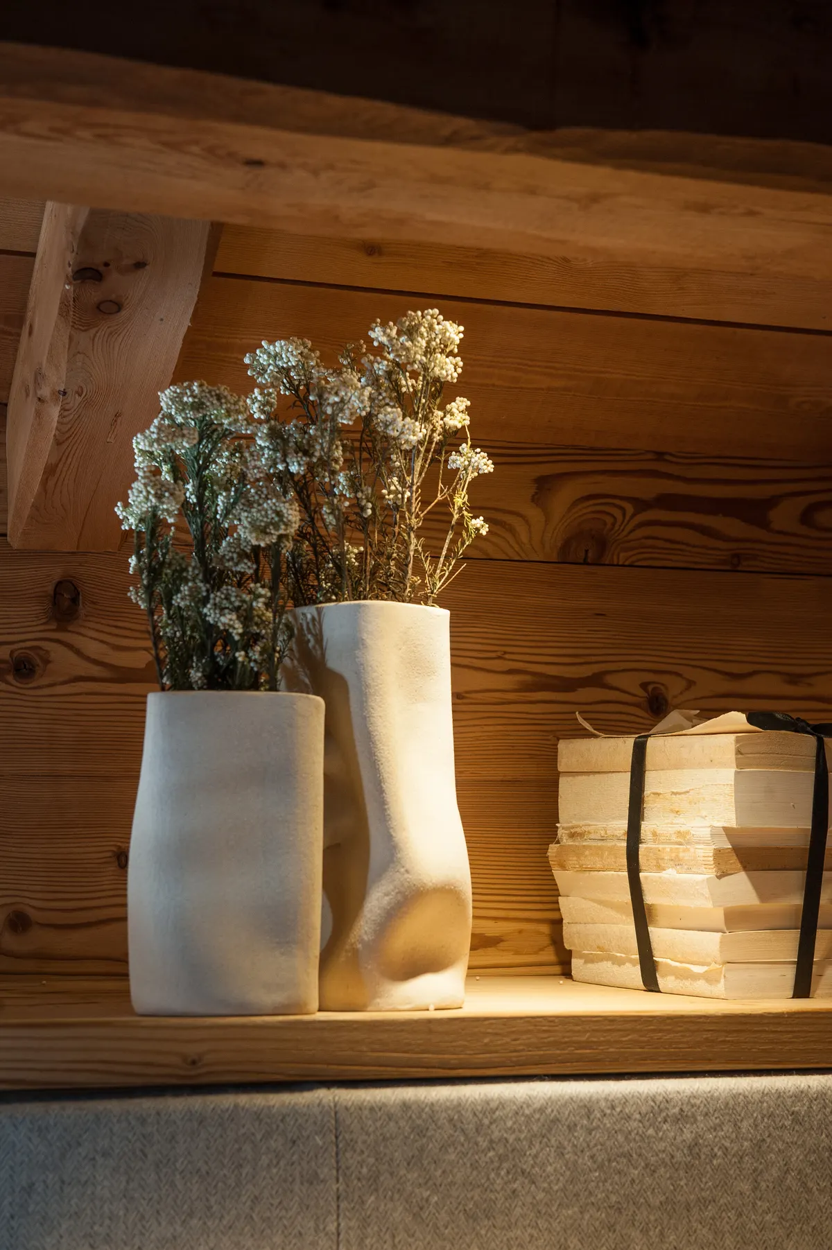 Bouquet de fleurs séchées dans un vase blanc sur une étagère en vieux bois
