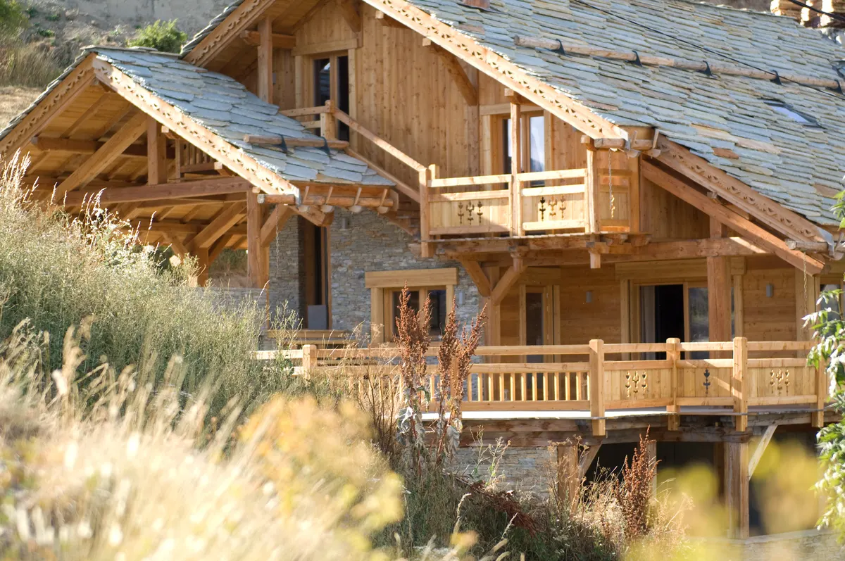 Façade du chalet en mélèze et balcons en bois en été
