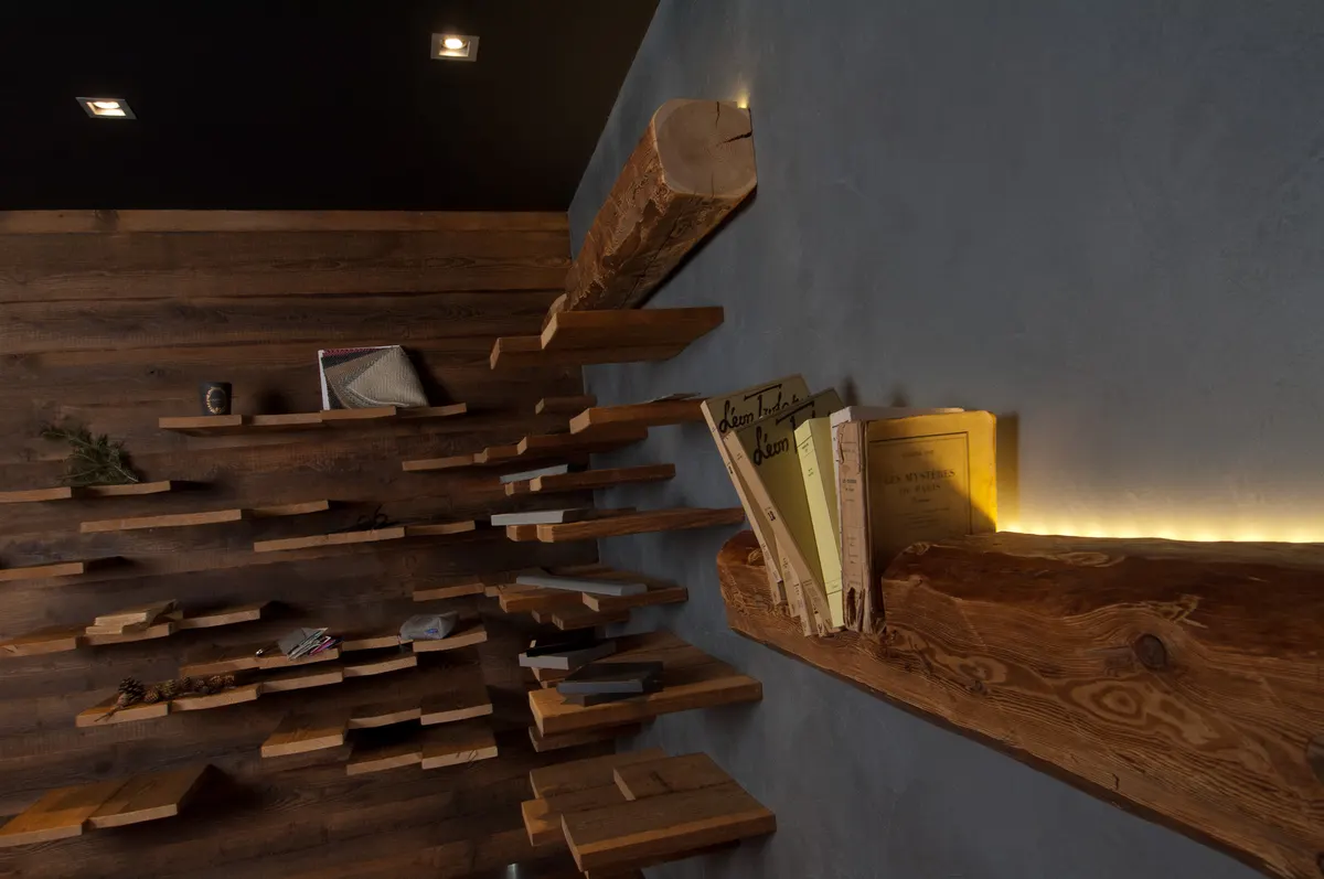 Étagère murale en planches de bois brut, revues et carnets rangés