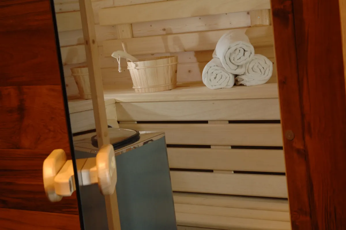 Sauna en bois clair, serviettes roulées sur les bancs