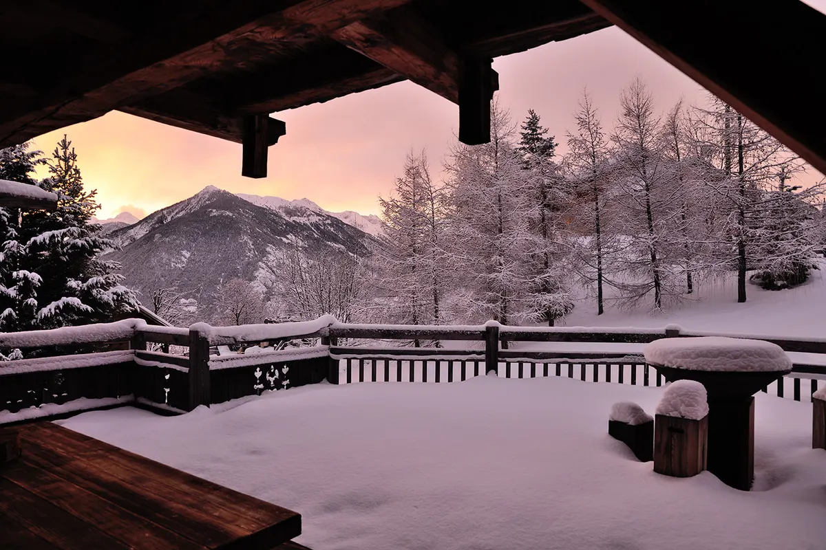Terrasse enneigée au coucher du soleil face aux montagnes