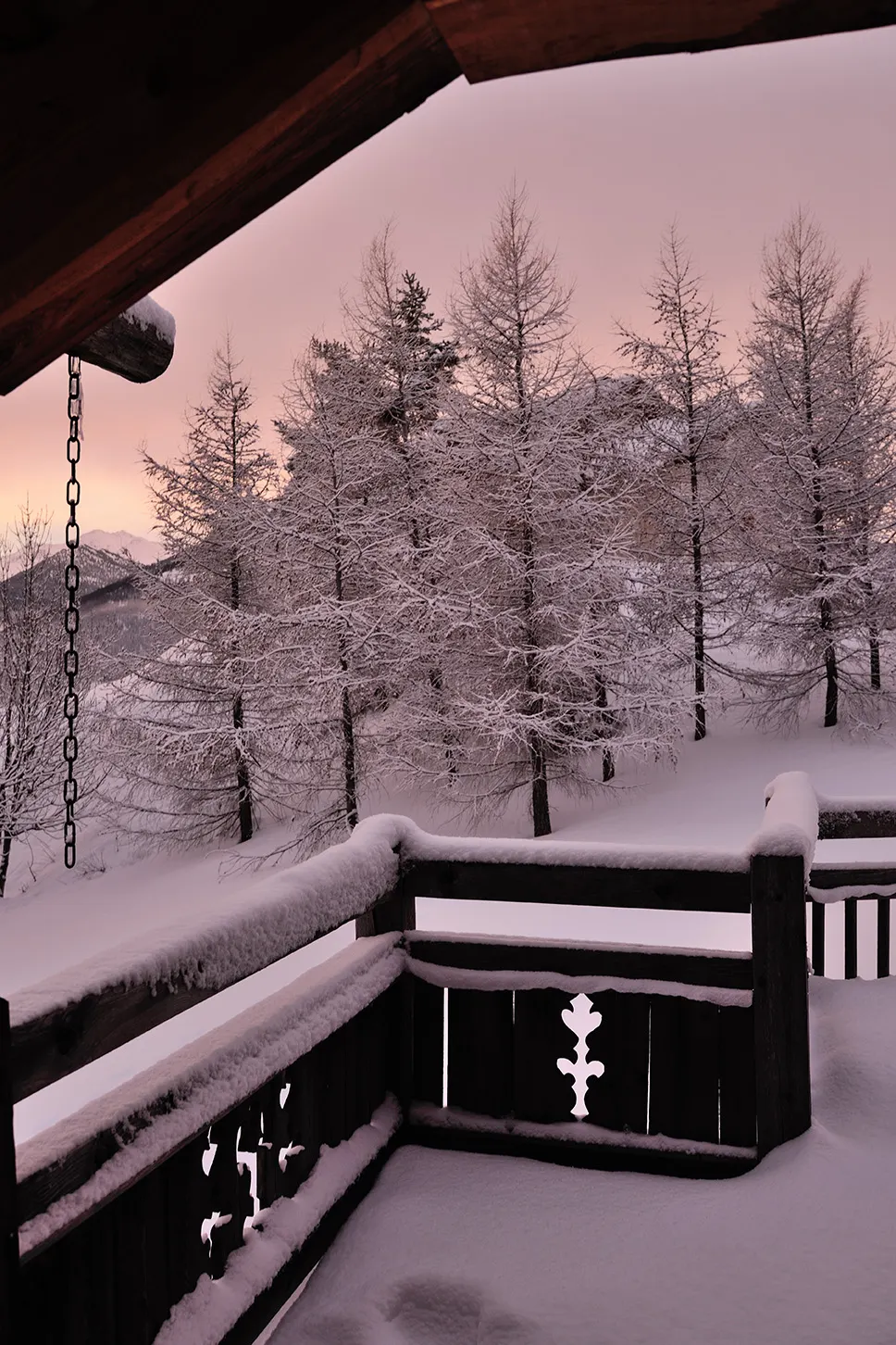 Balcon enneigé au crépuscule, mélèzes givrés en contrebas